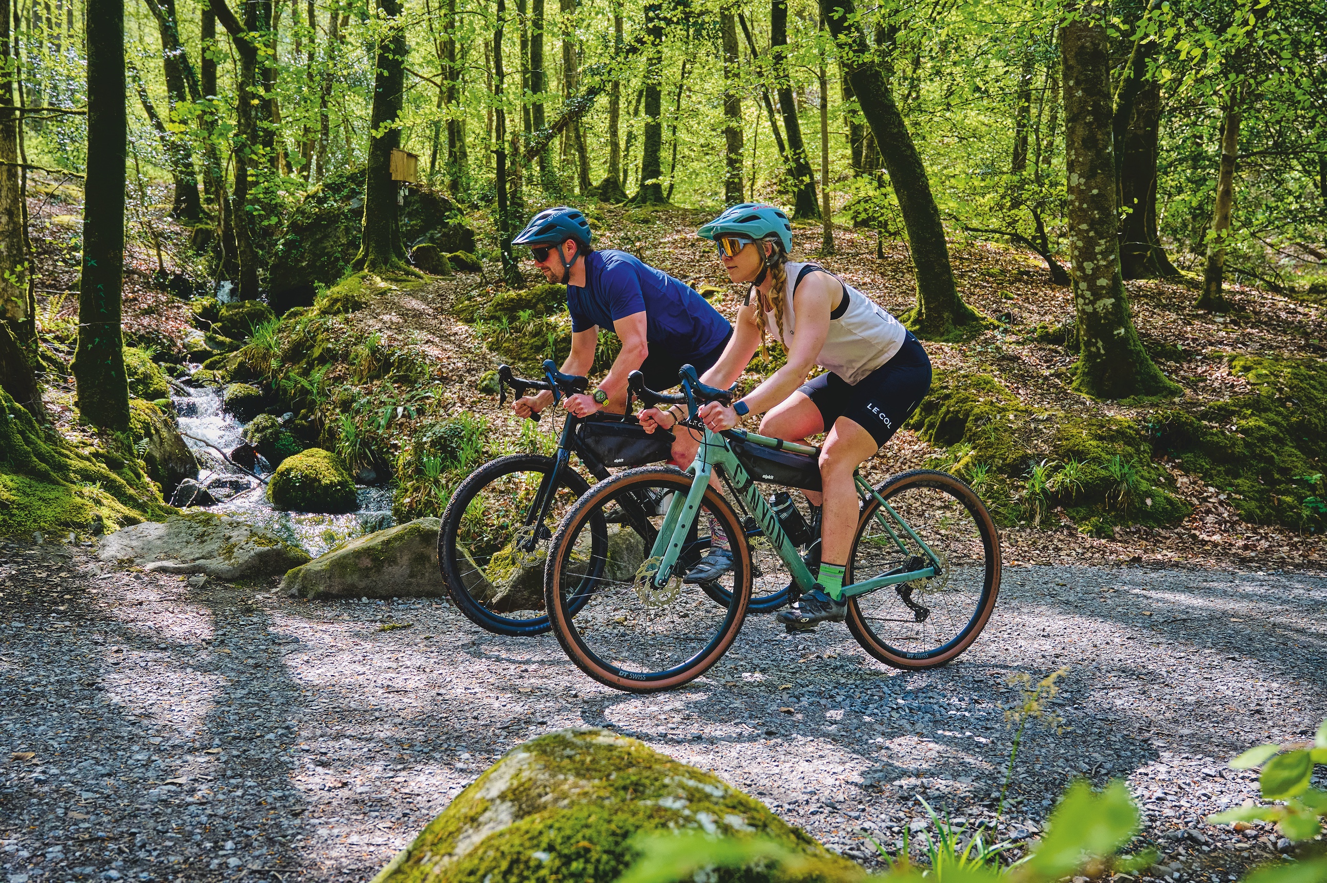 Two riders riding along a forest trail