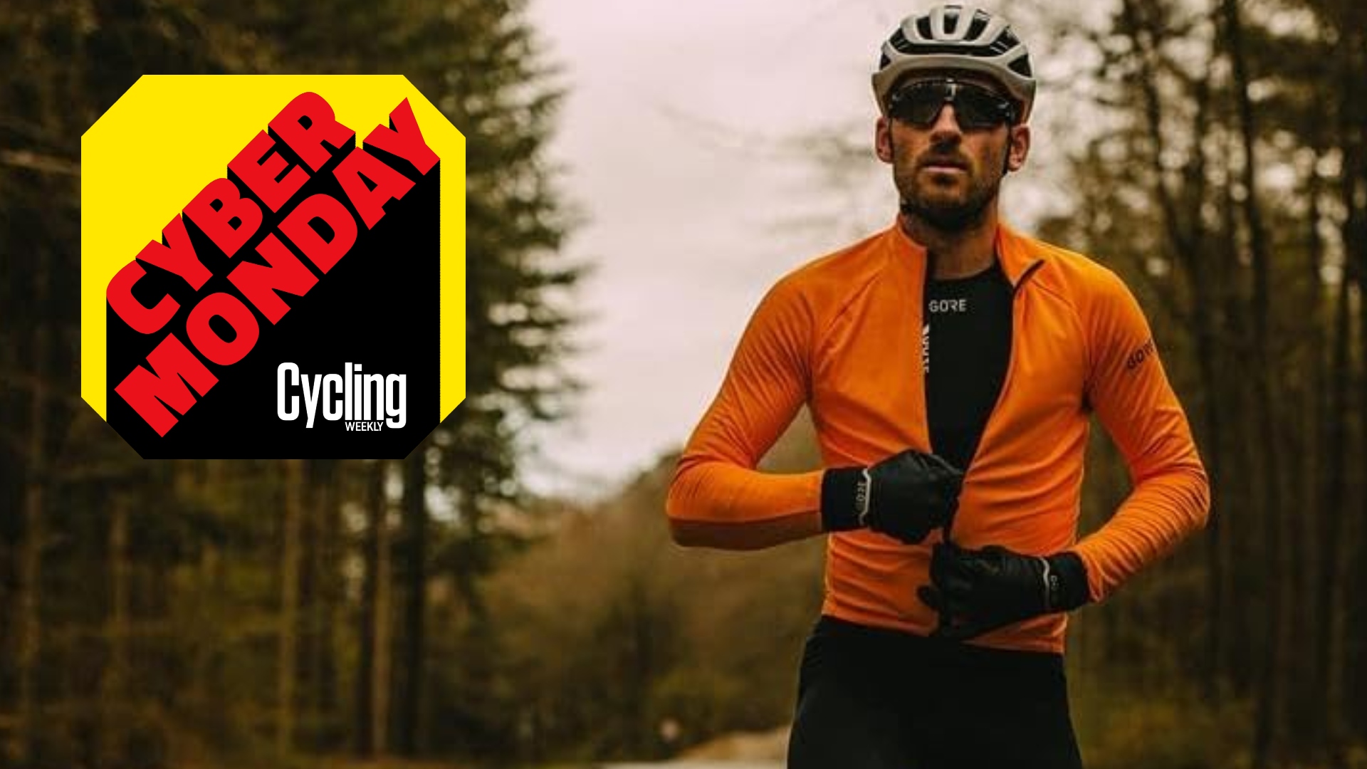 A male rider in an orange jacket rides with no hands and does up his jacket wearing a pair of Gorewear Gore-Tex Infinium gloves 