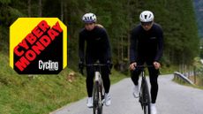 A female and male ride next to each other in Winter Le Col clothing on an alpine pass